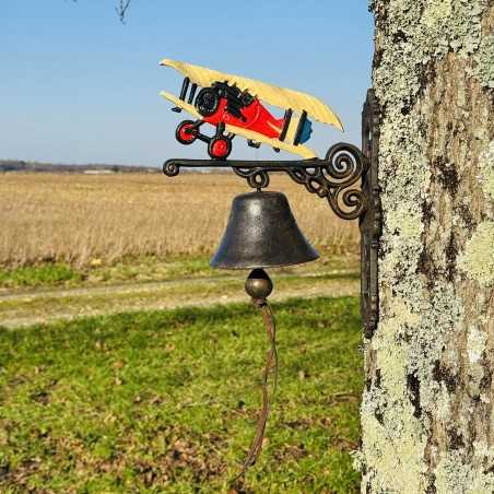 Campana murale in ghisa installata su una parete con un aereo biplano colorato